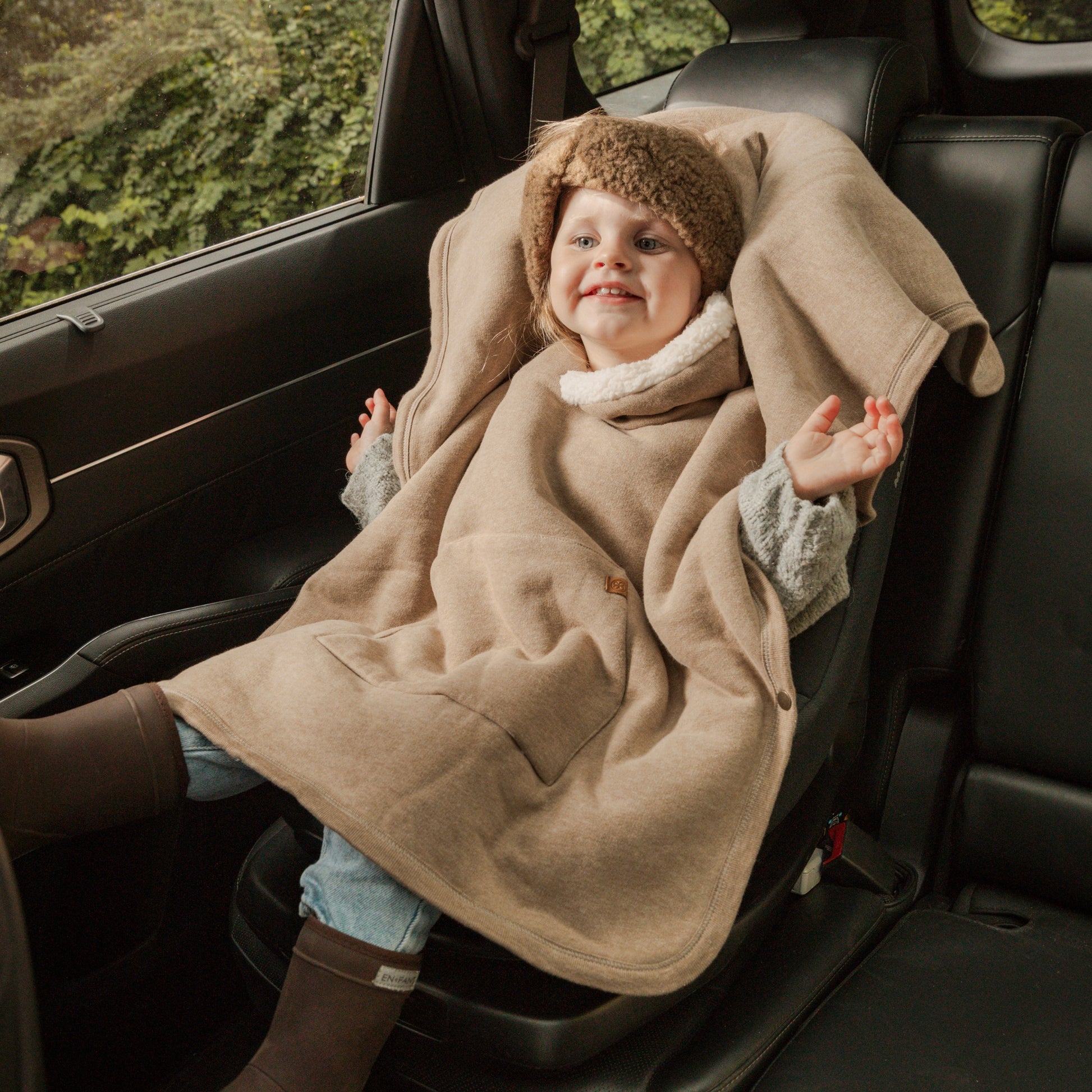 Kinderponcho voor de winter, gedragen over autostoel
